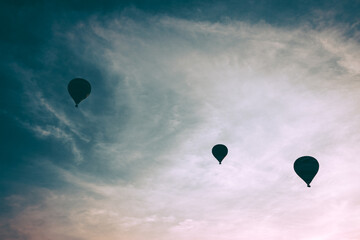 Three hot air balloons in flight during sunset
