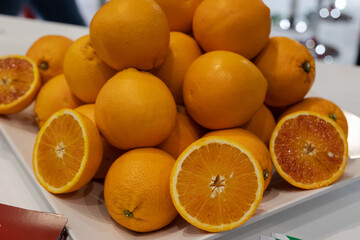 Group of Whole Oranges and Some Oranges Cut in Half inside a White Plate
