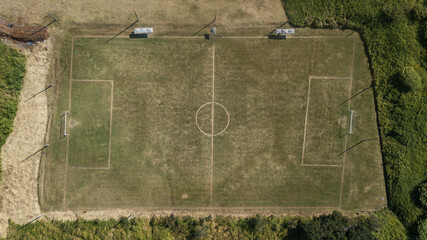 Drone view of a football field with crooked lines and weathered grass.
