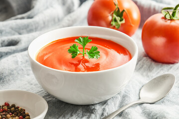 Close up bowl of tomato soup with parsley on tablecloth