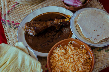Mole poblano dish with turkey accompanied by red rice and handmade corn tortillas