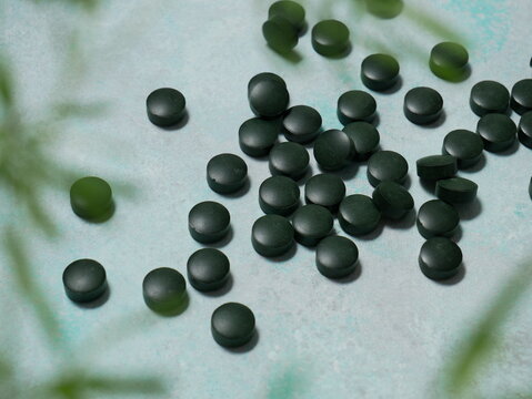 Comprim&eacute;s de Spiruline. Algue spiruline. Fond textur&eacute; bleu. Concept de sant&eacute;, nutrition et vitamines. Flat lay