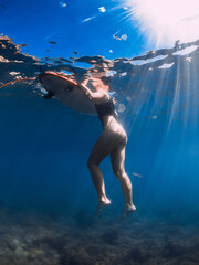 Girl swim with board in blue sea. Underwater photo with woman and surfboard