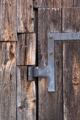 close-up of a rusty door hinge on an old door outside. Access to a barn made of weathered wood