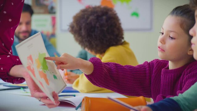Close up of female student looking at map in classroom geography lesson - shot in slow motion