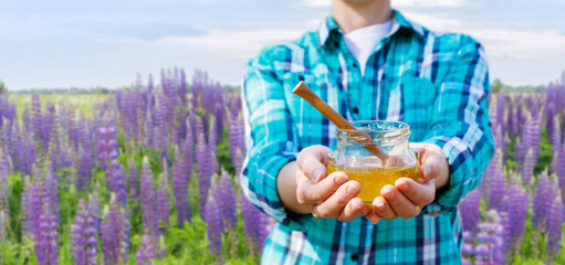 Farmer beekeeper shows honey in a jar .