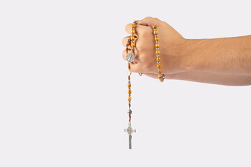 Folded hands of a young man holding a rosary during a pray isolated on white background - 512430221
