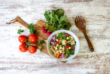 Homemade pasta salad and fresh ingredients on a white wood background