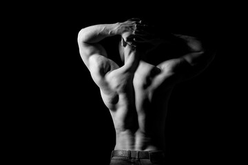Fototapeta na wymiar Strong muscular man holding his hands behind his head. Perfect shoulders and back muscles. Dramatic light