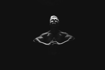 Handsome power athletic man in dramatic light. Strong bodybuilder with perfect shoulders, biceps, triceps, back, delta and chest. Strength and motivation