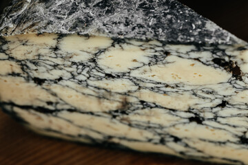 Asiago italian cheese with cuttlefish ink on a wooden board. Food recipe background. Close up