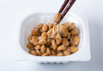 糸を引く納豆（パック入り丸大豆納豆を箸でつかむ）