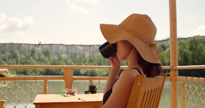 Woman pleasure and relaxing, drink tea on terrace by lake at morning. Hedonism concept