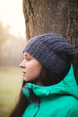 Pleasant and pretty brunette in a winter jacket and knitted hat is looking at her friends and enjoying the feeling of freedom. Candid portrait of smiling czech girl