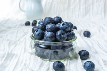 Fresh ripe blueberries in a glass on a white cloth