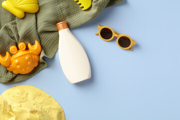 Flat lay baby sunscreen and summer accessories on blue background.