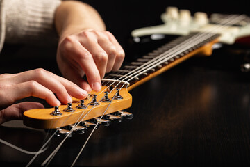 The hands of a guitarist changing strings on an electric guitar