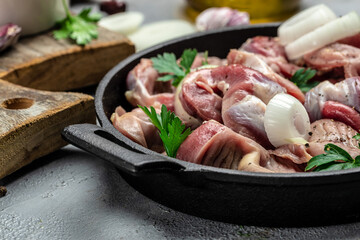 Raw uncooked chicken gizzards, stomach on a wooden background. Traditional Korean spicy chicken meat. Food recipe background. Close up