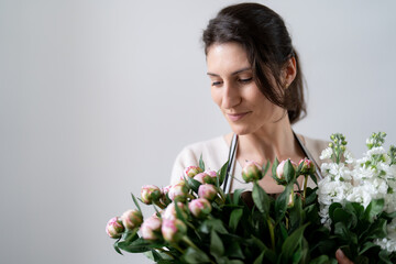 WOMAN florist EMBRACING a bunch of white and pink flowers on white background indoors