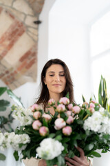 Positive woman holding a huge bouquet of flowers in her office. Birthday present smile.