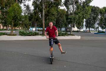 Obraz premium Attractive man riding a kick scooter at cityscape background.