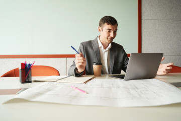 Worker with pen and coffee using laptop at workplace