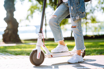 Legs of woman riding electric kick scooter. Ecological transportation concept.