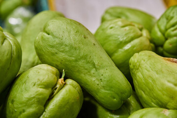 Green chayotes placed on a shelf for sale inside a market