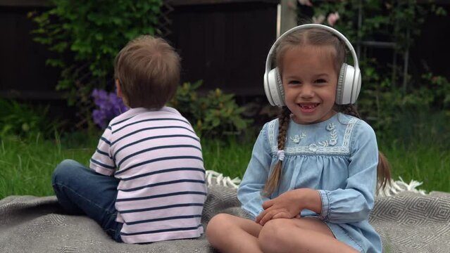 Two naughty Siblings dont share. boy ans girl listening to music on headphones outside. Children and technology. Brother Sister. Love of music, dreams hobbies. Childhood, musicality, hobby. Friendship