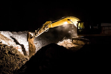 Tractor excavator worker digs a trench on a construction site at night long exposure
