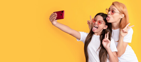 Mother and daughter child banner, copy space, isolated background. happy mom and kid making selfie on smartphone showing peace, blogger.