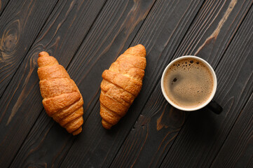 Croissants with coffee on a wooden background.