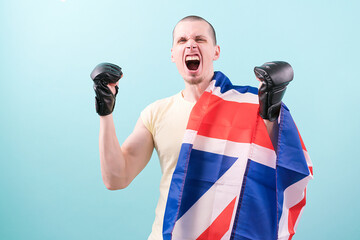 A crazy screaming MMA fighter in black gloves standing on a blue background and holds a UK flag....
