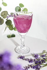 Purple drink with lavender syrup,ice cubes and and lavender flowers on grey background.