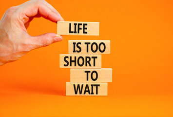 Life is short to wait symbol. Concept words Life is too short to wait on wooden blocks on a beautiful orange table orange background. Businessman hand. Business motivational life or wait concept.