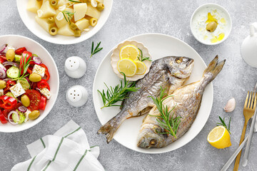 Dorada fish sea bream baked, fresh vegetable greek salad, boiled potatoes with garlic and olives and tzatziki dip. Healthy food. Mediterranean diet.