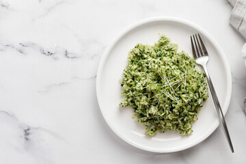 Spinach Rice with microgreens on white plate with fork on marble Background, Healthy Vegetarian diet Food. Green Rice with Spinach.