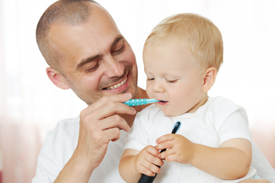 Father teaching baby boy brushing teeth. The concept of oral hygiene from the first tooth