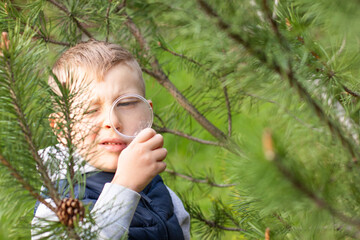 A little boy with a magnifying glass is studying the world around him