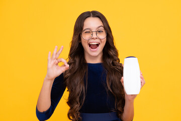 Child with shampoo conditioner. Daily cosmetic care. Teenager kid 12, 13, 14 years old hold bottle of hair and skin care. Beauty health and cosmetics. Happy face, positive and smiling.