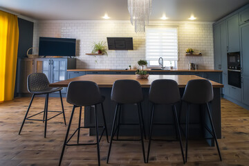Interior of modern kitchen with wooden floor and large table in center of room.