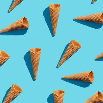 Empty wafer ice cream cones continuous pattern on blue background .Isoclate top view, hard light
