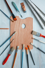 Palette, paintbrushes and palette knife, canvases  on rustic table. Copy space