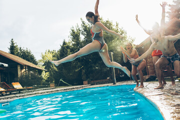 A young group of friends jumping into the swimming pool.Having fun and refreshing on a hot summer day.	
	

