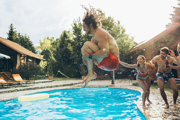 A young group of friends jumping into the swimming pool.Having fun and refreshing on a hot summer day.
- 512453416