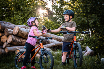 cute children on a bicycle sharing a bottle in summer