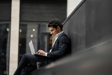 Using a laptop, a financier goes to a new office, a man in a business suit, a happy employee