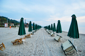 Empty beach with folded umbrellas and chairs at the end of the day