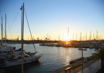 Fototapeta na wymiar Yachts and boats in silhouette of sunset in Marina. Sunset at port. Skiff and Sailboat in harbour. Luxury yacht and fishing motor boat in yacht club at Mediterranean Sea. Yacht in sunrise in Harbor.