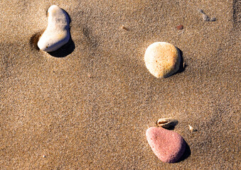 Fototapeta na wymiar Stones on sand at beach. Sea stones background at seashore. Colored stone on coastline. Stone on sand background at sea beach. Pebbles at coast. Pebble as abstract natural background. Sea stones. .